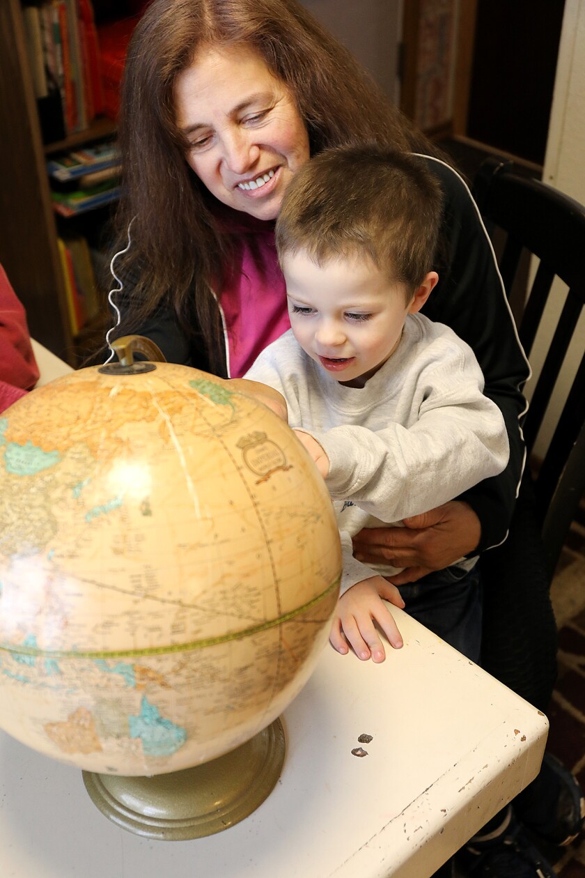 Diana Deeth holds Rocky Miller, 3, as he looks at a globe