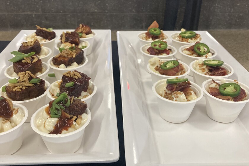 Paper cups inside of serving dishes containing macaroni and cheese.