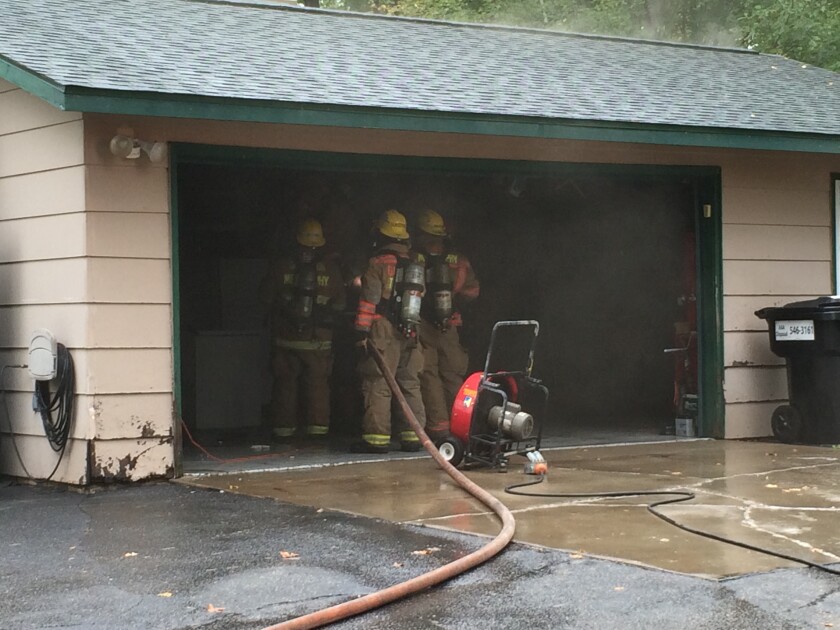 Garrison firefighters make sure the fire is out in the walls and attic of the garage located between Brainerd and Garrison. (Jennifer Stockinger)