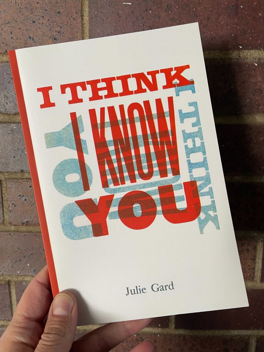 White person's hand holding paperback book: "I Think I Know You" by Julie Gard. Cover features letterpress-style title text.