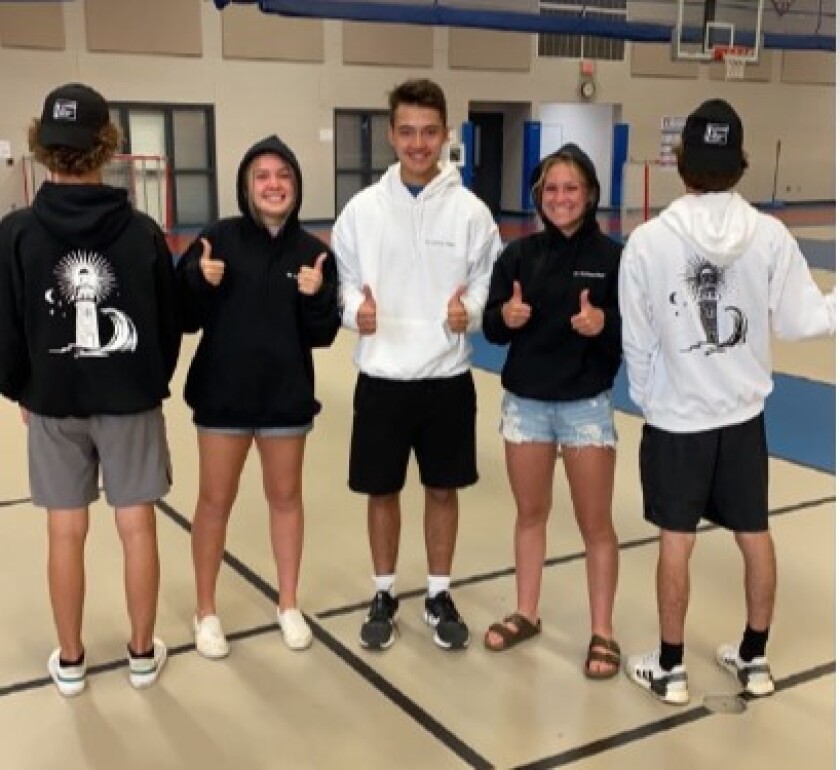 Young people do a thumbs up standing next to each other.