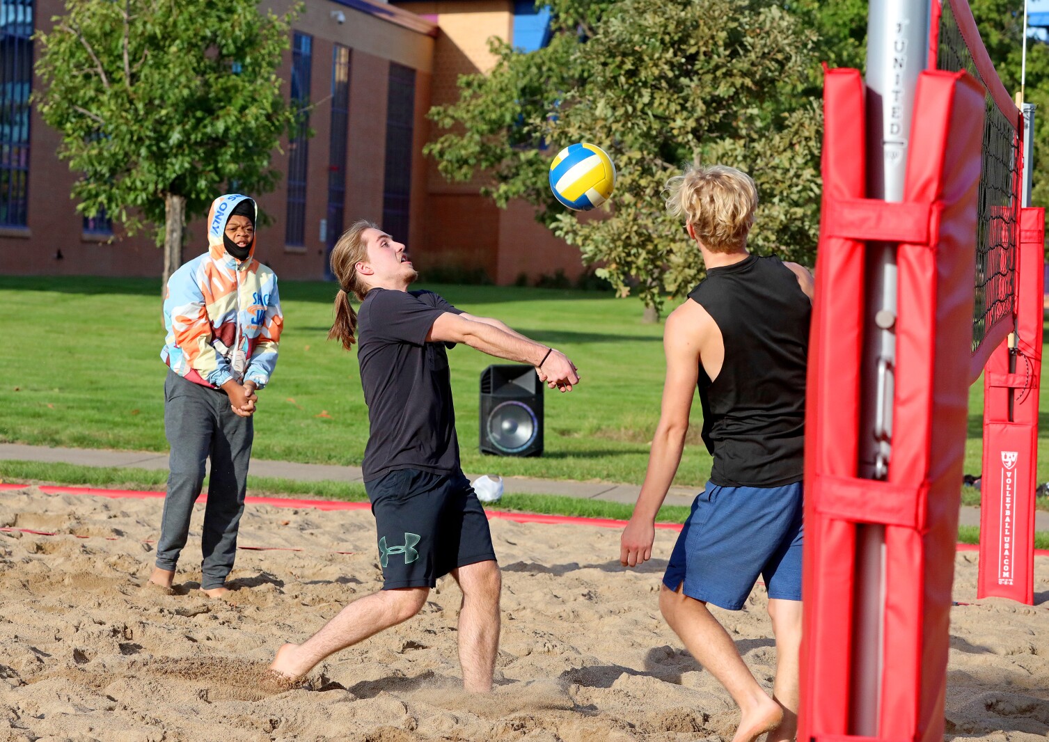 Volleyball players compete outside on the sand volleyball courts at CLC.