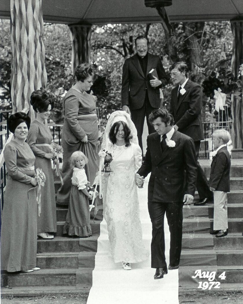 A young couple leaves a gazebo after being married. People are smiling