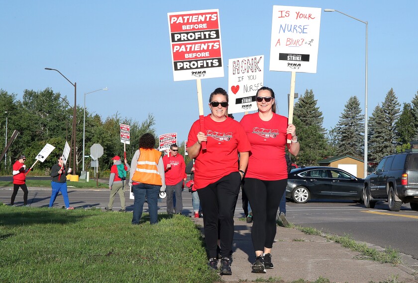 Meg Meierhoff, left, of Duluth, and Alex Lehman, of Lake Nebagamon, smile as they carry signs with other members of the Minnesota Nurses Association while striking outside of Essentia Health St. Mary’s Hospital in Superior