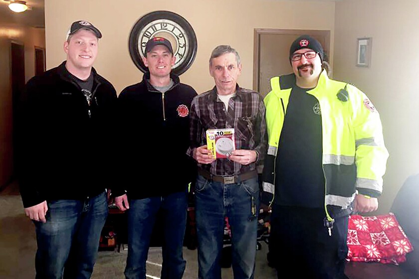 Rice Lake home owner John Helgeton (middle) holds a new smoke alarm given to him by Rice Lake volunteer fire fighters (from left) Travis Samuelson, Mike Conradi and Andrew Alander. The fire fighters installed the smoke alarm in Helgeton’s home as part of an effort to increase fire safety in the community.