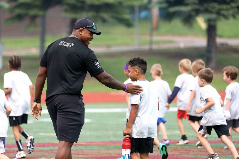 A pro football player patting a kid on the back during a youth camp.
