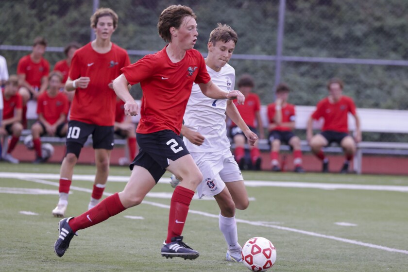 High school boys soccer players in red uniforms playing players in white uniforms outdoors