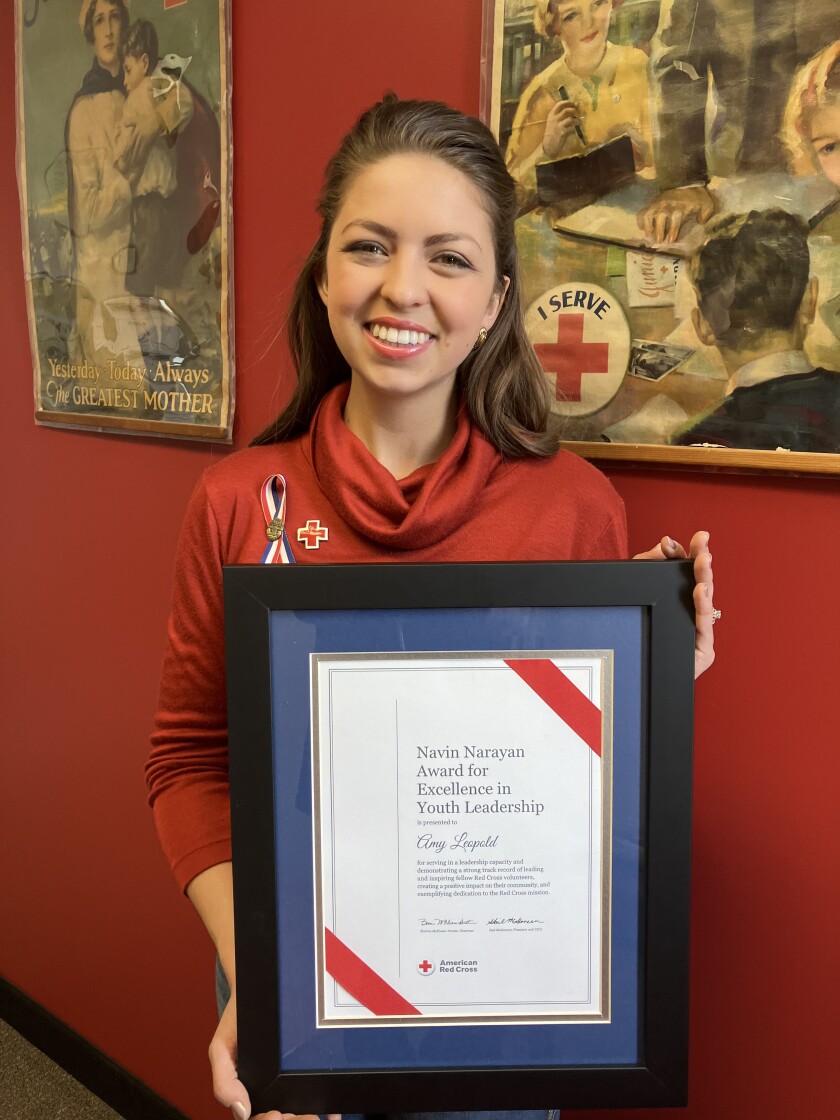 Woman holds a framed certificate of the Navin Narayan Award for Excellence in Youth Leadership