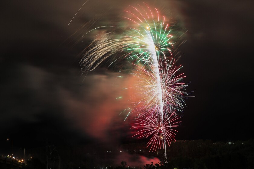 Large aerial fireworks burst in cloudy foggy night sky