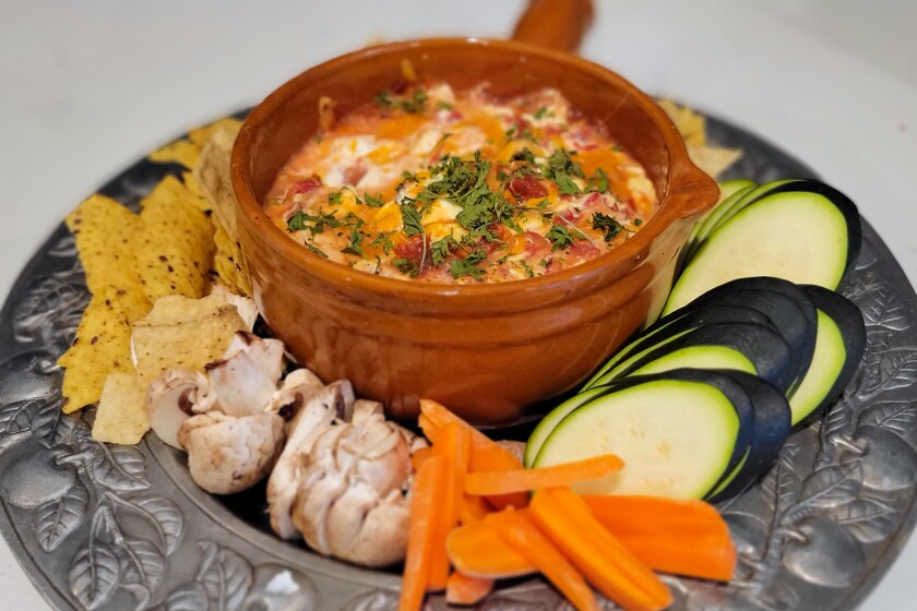 Chile Con Queso Dip on a plate with chips and veggies