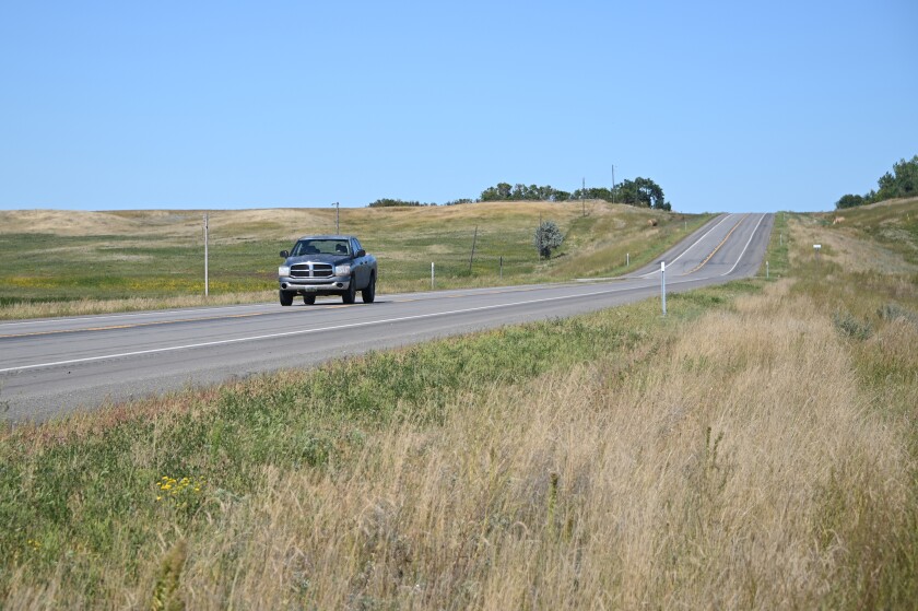 Two-lane highway in a rural setting in North Dakota with a pickup traveling along