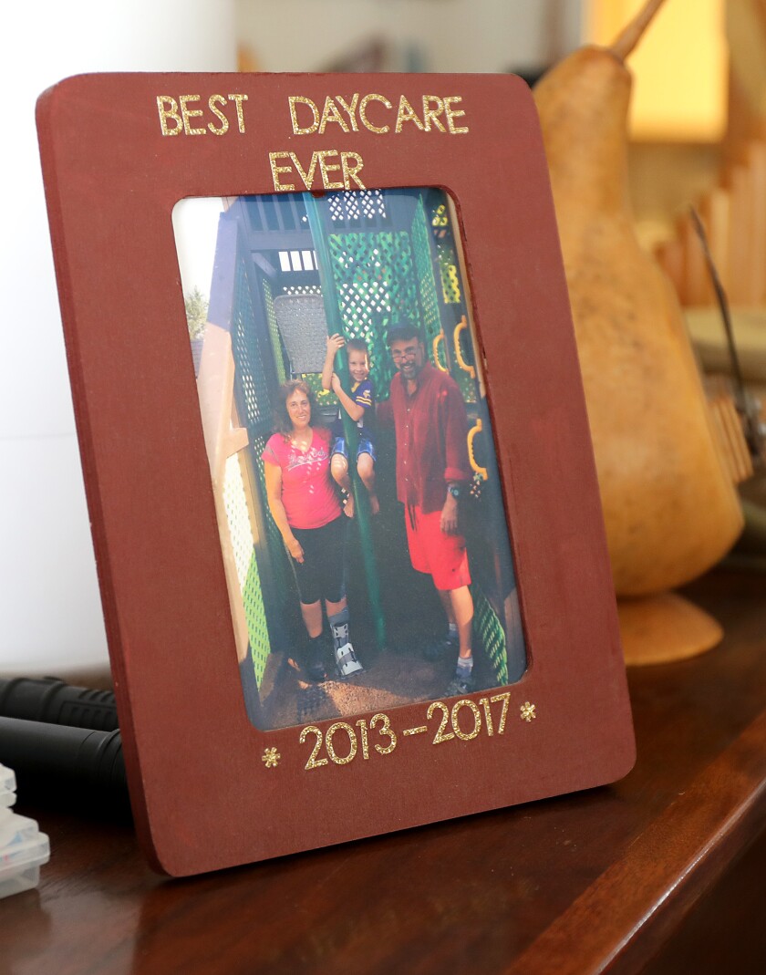 A picture of David and Diana Deeth with a child that attended their day care is framed in a Best Daycare Ever picture frame
