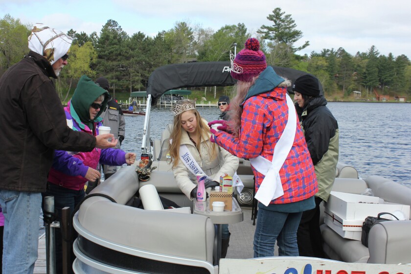 Miss Nisswa Princess Taylor Leas, left, and Miss Nisswa Hannah Gatton serve hot coffee and doughnuts to an angler on a dock at Zorbaz on Gull on Saturday, May 14, as part of the annual Welcome Wannigan, sponsored by the Nisswa Chamber. Photo by Nancy Vogt
