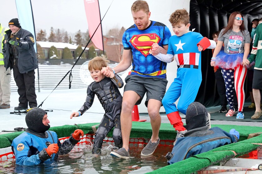 People jump into the water during the Polar Plunge event on Pelican Lake.