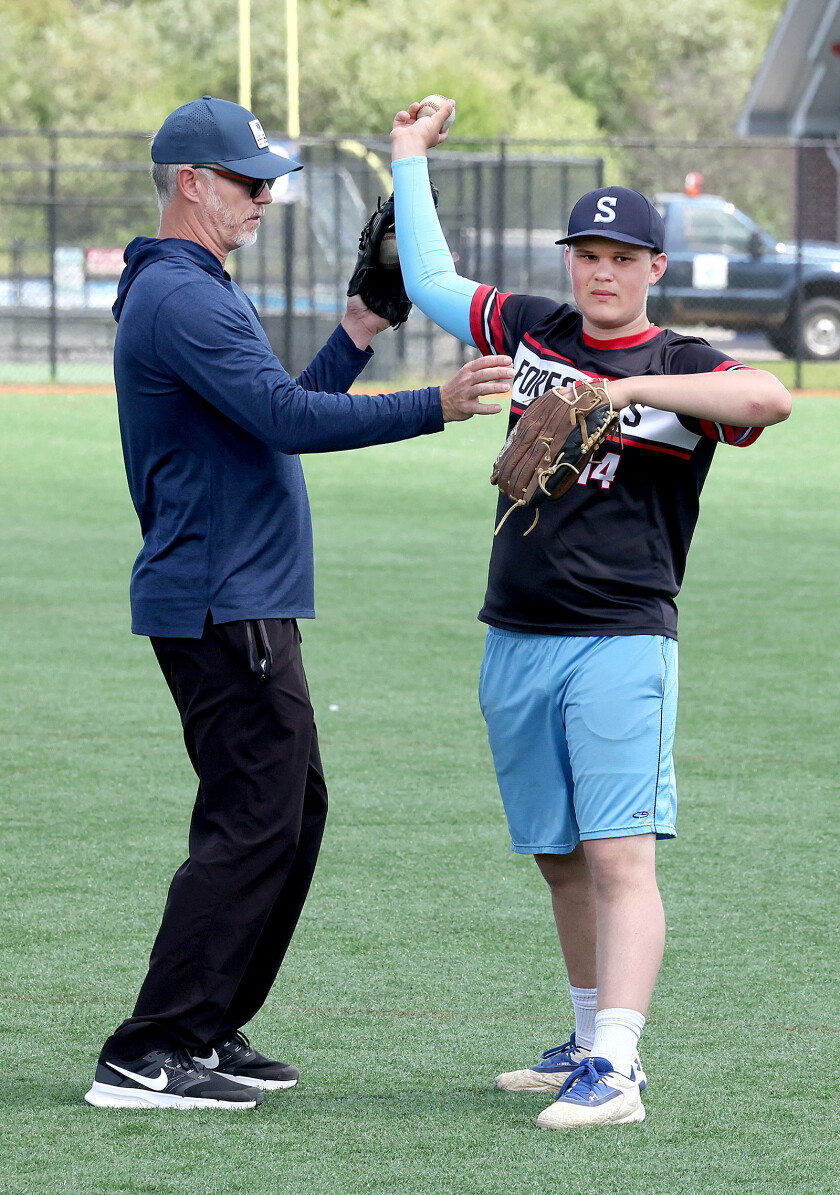 Pitcher shows correct form to young pitcher.