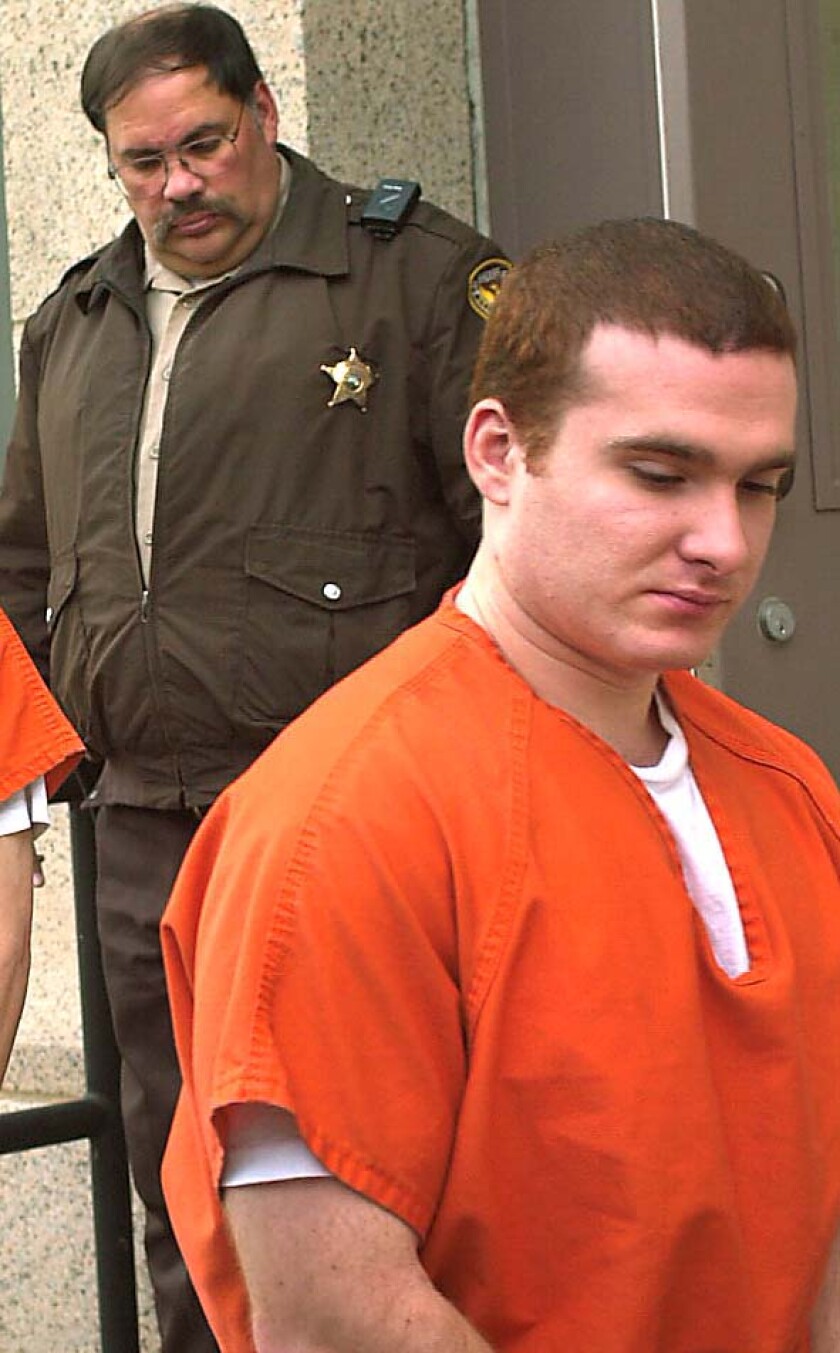 prisoner in orange jumpsuit followed by uniformed sheriff's deputy