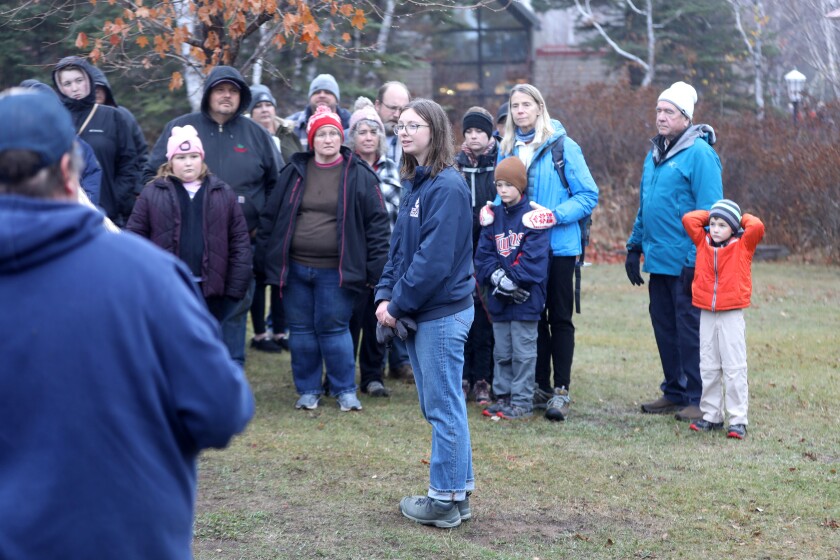 A woman speaking to a crowd of people while giving a tour outdoors.