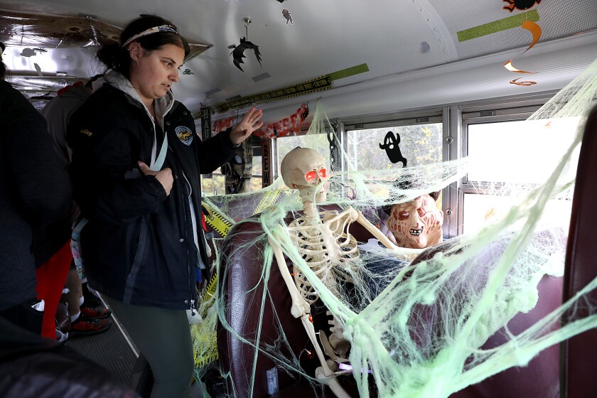 Bus driver Ashley Gustafson checks on the skeleton after turning on its eyes inside the haunted school bus