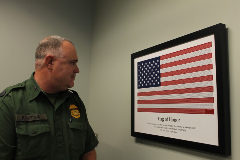 Robert Tuttle, a U.S. Border Patrol agent in charge of the Warroad (Minn.) Station, looks over the "Flag of Honor," an illustration that names all of the victims killed in the Sept. 11, 2001, terrorist attacks, while at the U.S. Customs and Border Protection's Grand Forks Office. (April Baumgarten/Grand Forks Herald)
