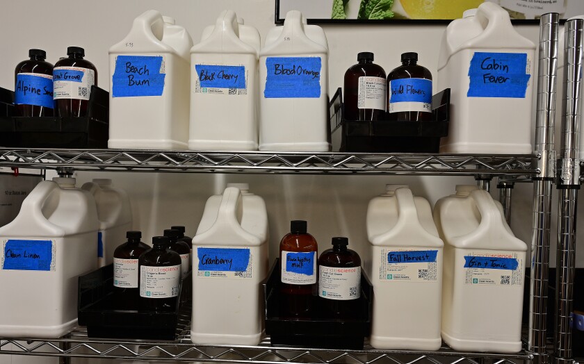Bottles of solution are lined up on two shelves, each container labeled with a certain scent.