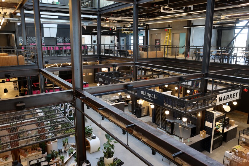 From the second floor, a view looks down at the raw bar on the first floor. I-beams criss-cross the space, and natural light floods in through larger windows.