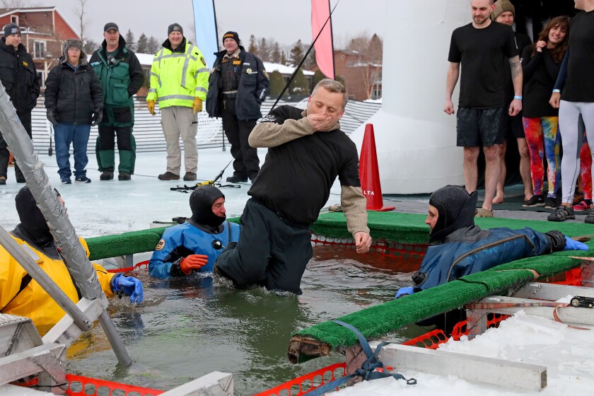 People jump into the water during the Polar Plunge event on Pelican Lake.
