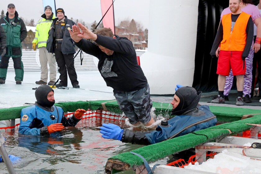 People jump into the water during the Polar Plunge event on Pelican Lake.