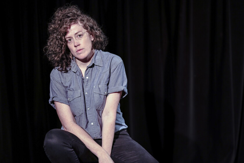 mulher sentada no palco com iluminação teatral