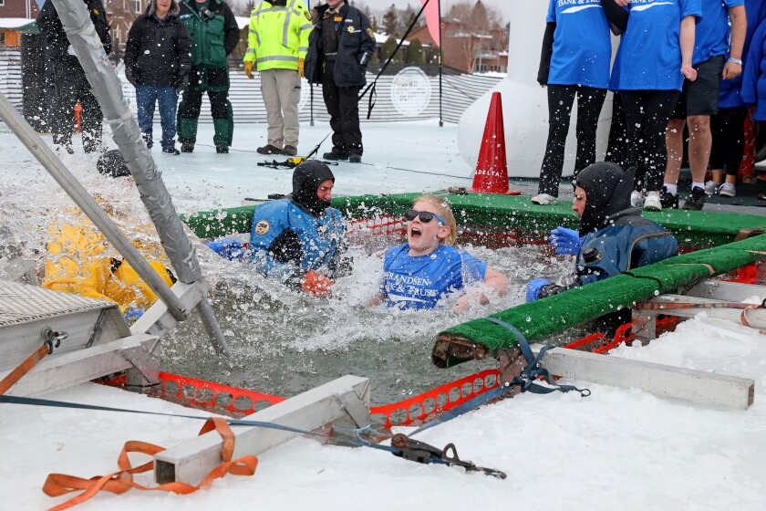 People jump into the water during the Polar Plunge event on Pelican Lake.