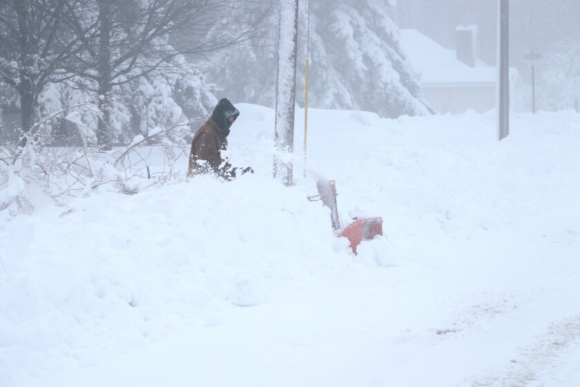 Man snow blows driveway.