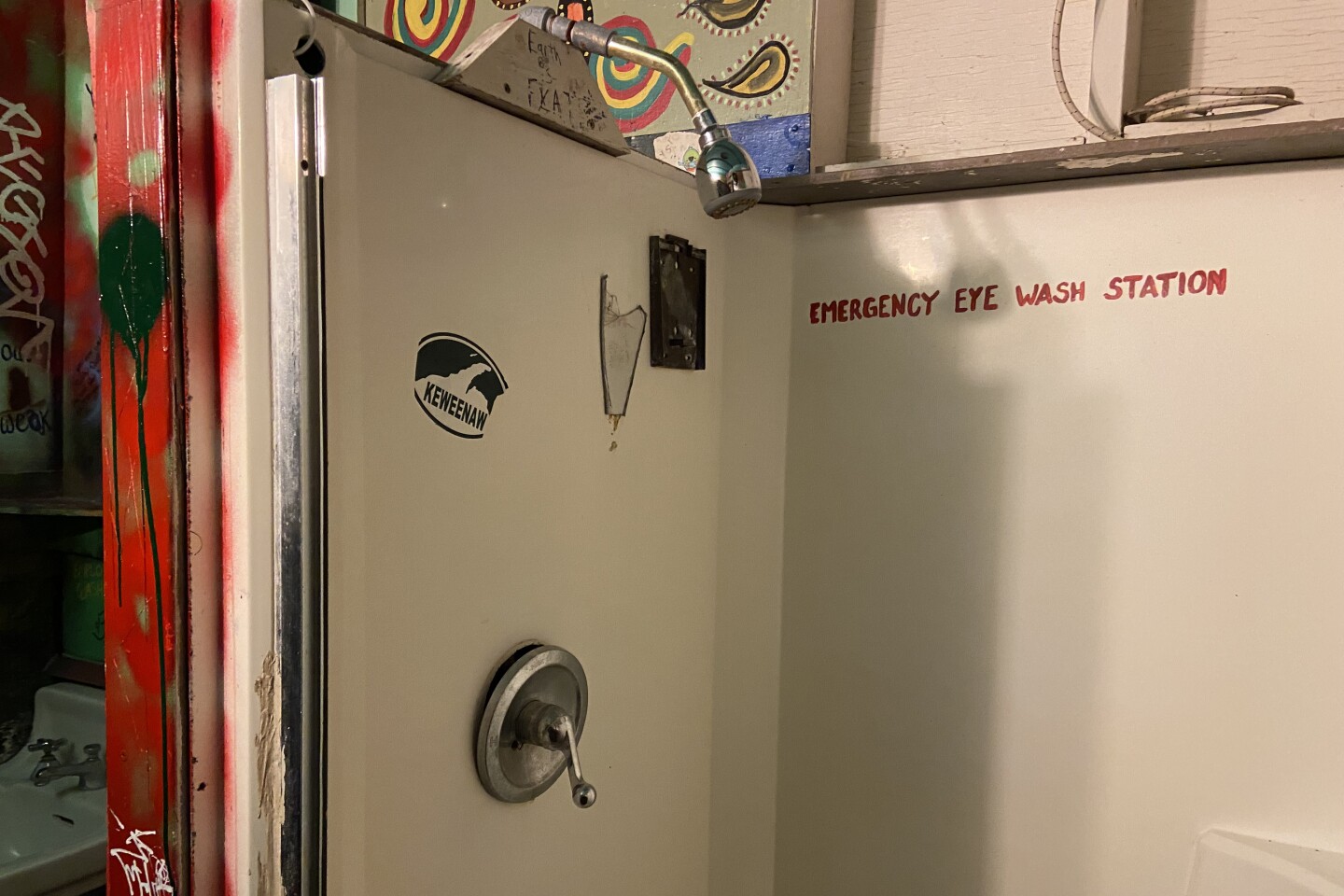 "emergency eye wash station" is painted in red on a white shower stall