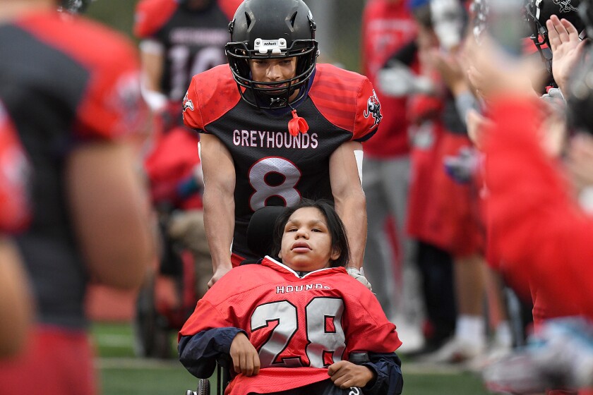 Duluth East’s Gabe Logan (28) gets a push from Preston Dallek (8) as Logan is announced before the Greyhounds game with Cloquet