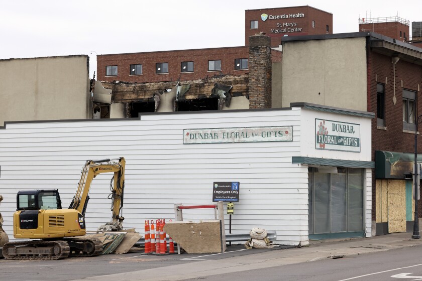 A mini-excavator sits outside a building.