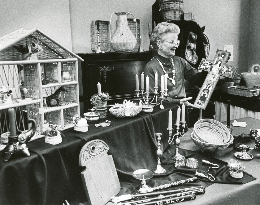 Sharon von Druten holds a cross nears tables of goods to be sold at Pilgrim Congregational Church.