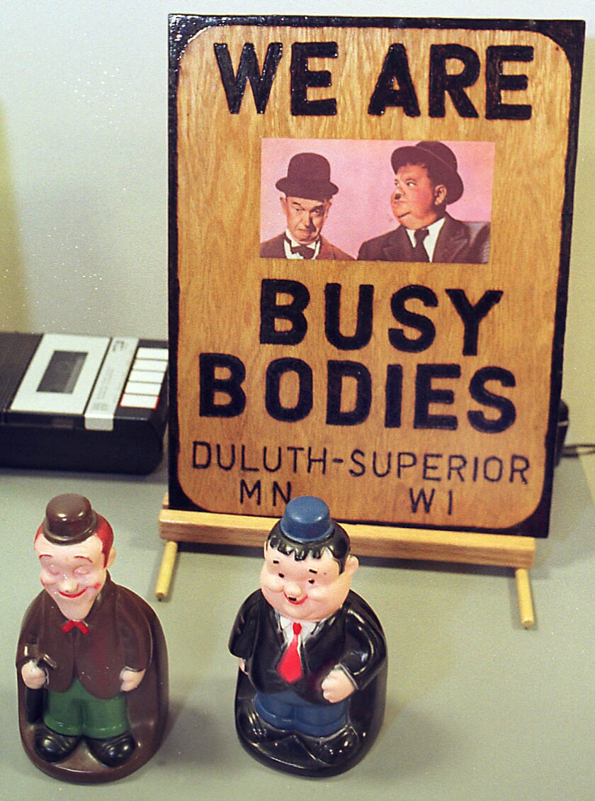 Sign that reads "We are Busy Bodies" and small statues of Laurel and Hardy