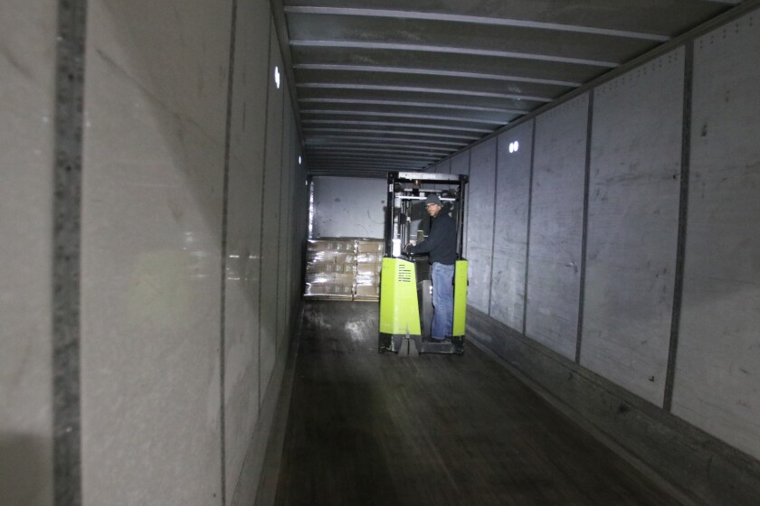 A man operates a forklift in a nearly empty trailer.