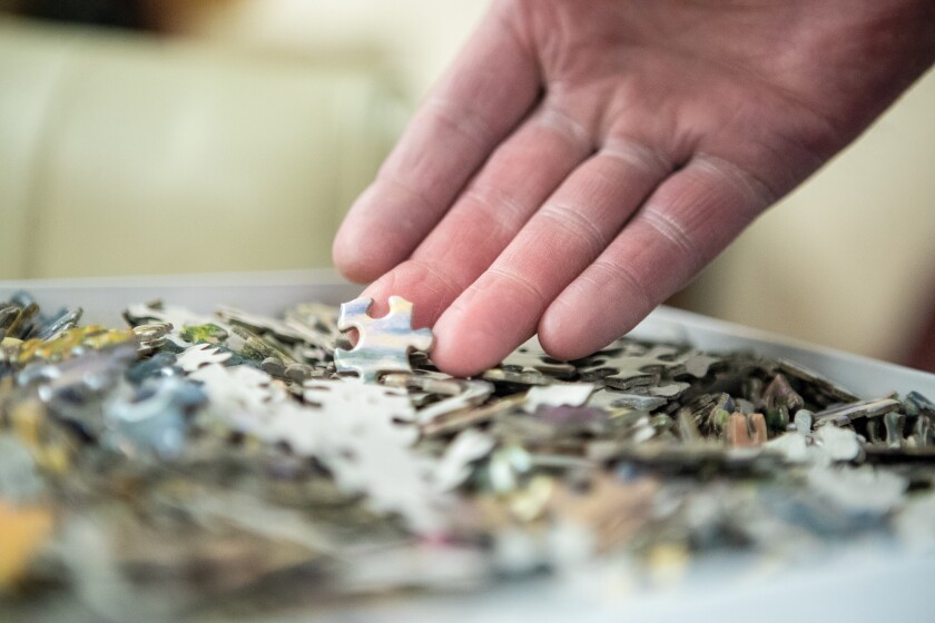 Bob Rodenberg sorts through a bin of puzzle pieces at the GlenOaks Senior Living Campus in New London on Tuesday, March 29, 2022.
