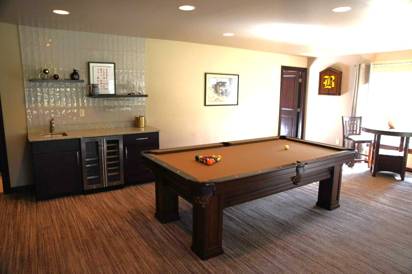 A pool table and bar sit in the basement of a home.