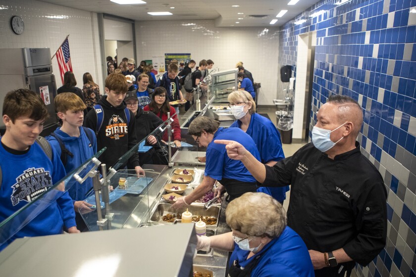 Taher corporate chef John Sugimura talks to students as they go through the cafeteria lines at BBE High School March 23, 2022.