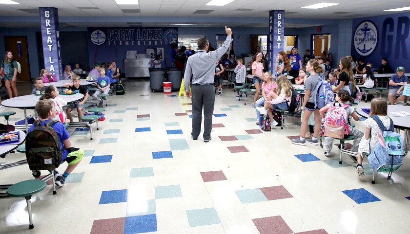 Great Lakes Elementary principal Ryan Haroldson, center, talks to some of his students about how the morning process will work as they eat breakfast