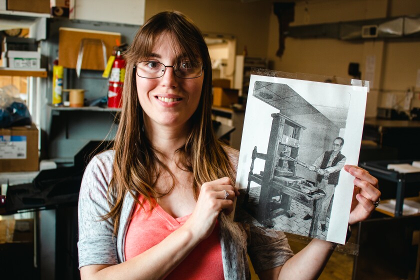 Ciera Jobgen holds a photograph of her grandfather at work at the Farmers Publishing Company newspaper in Bagley in its early days. He died on the job.