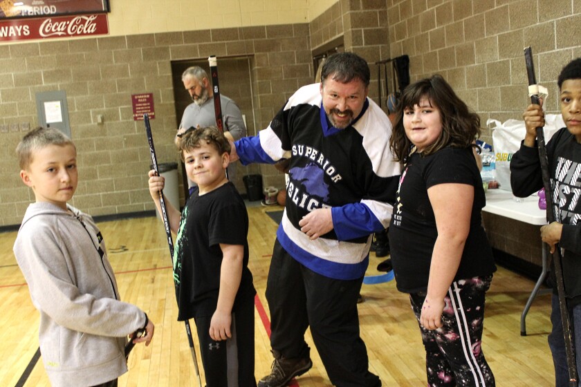 Senior Constable Joel Markon poses for a photo with young hockey players during the annual community floor hockey game Wednesday, Feb. 20, 2019 at the YMCA of Superior-Douglas County.