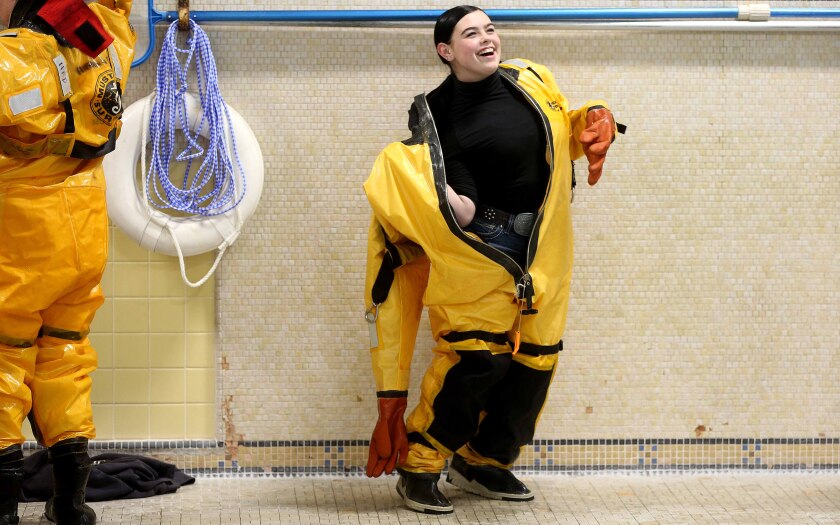 High School student smiles while putting on a fire department water rescue suit