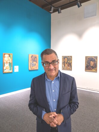 Duluth Art Institute board president Robin Washington stands in an art gallery in front of four paintings by his late mother, artist and activist Jean Birkenstein Washington.