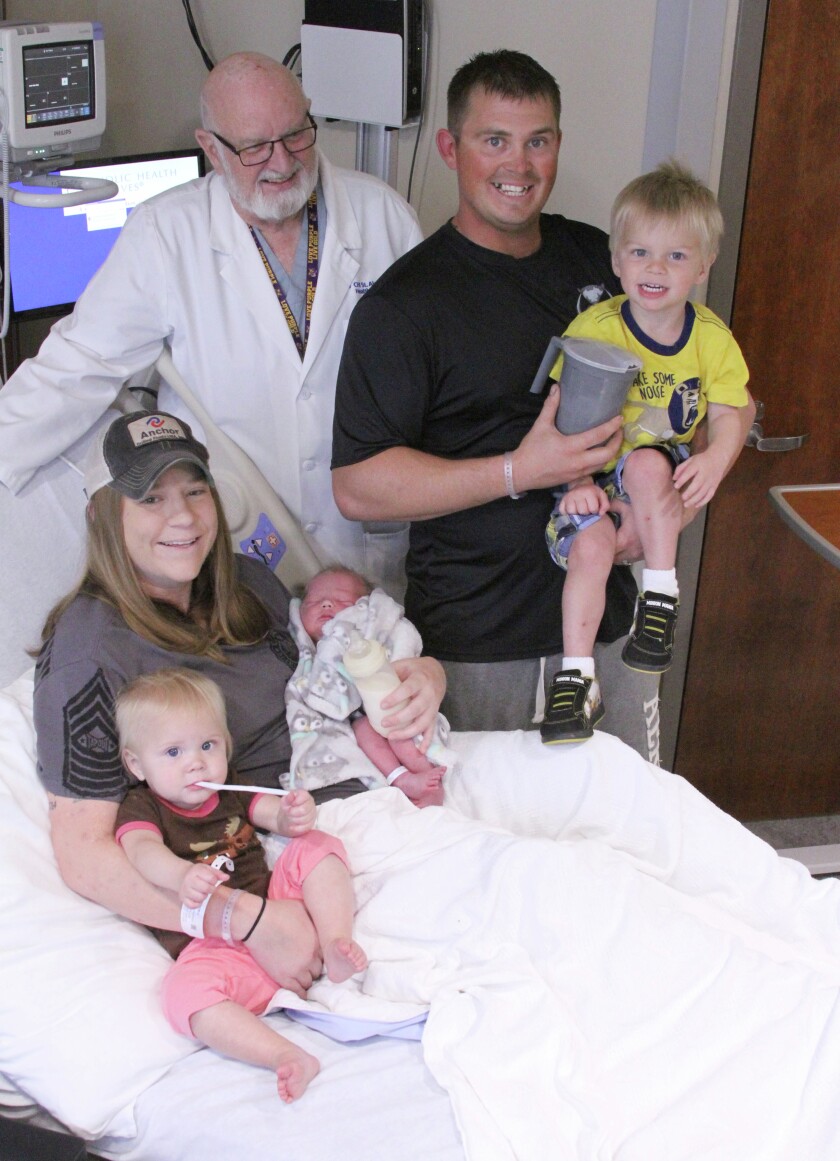 Dr. William Lowe, an obstetrician at CHI St. Alexius Health in Dickinson, stands next to Seth Stevenson and his 2-year-old son, Axel, while his wife, Lauren Stevenson, sits with 1-year-old Tommie, left, and newborn Henry on Friday in their hospital room. The three siblings, all of whom were delivered by Lowe, were all born on Sept. 1. (Dustin Monke / The Dickinson Press)
