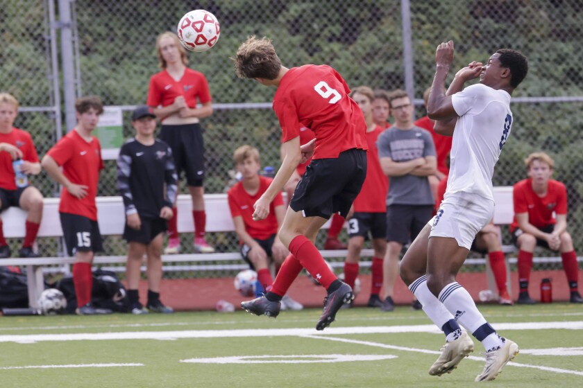 High school boys soccer players in red uniforms playing players in white uniforms outdoors