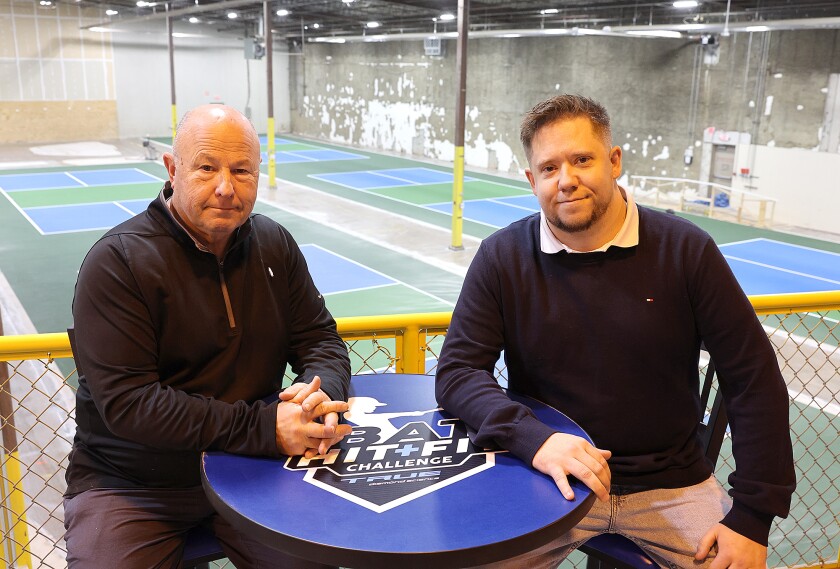 Men sit above pickleball courts.