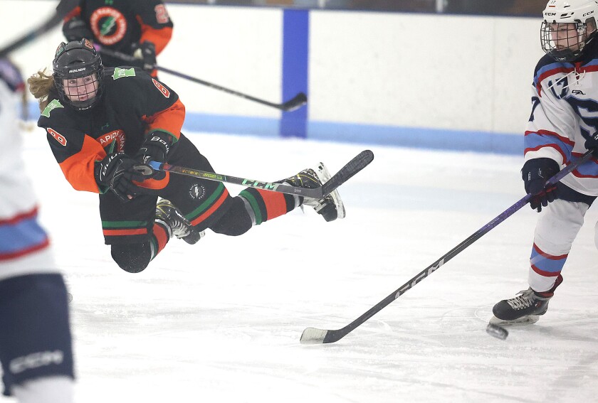 Player flies through air as she shoots puck.