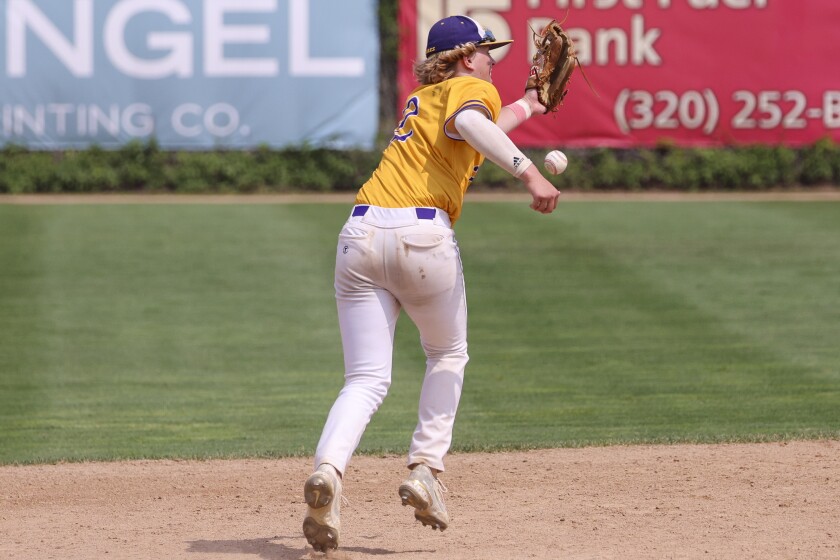 High school baseball players play on outdoor field on sunny day