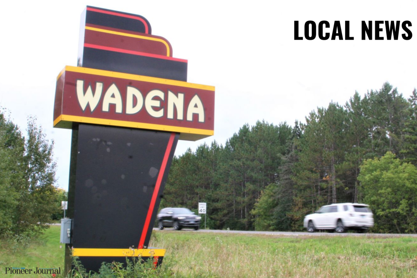 Sign saying, "Wadena" with cars driving past.